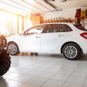 The interior of a home garage with a white SUV and an ATV parked inside
